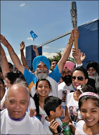  ??  ?? Baton bearer Dilawer Singh was all smiles as he carried the the Queen’s Baton in Glasgow