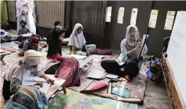  ?? TATAN SYUFLANA AP ?? At her home in Tangerang, Indonesia, teacher Inggit Andini, right, has offered classes for students who lack access to the internet to study online.