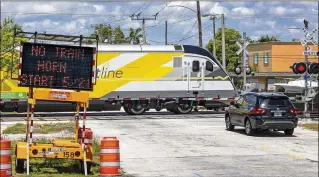  ?? LANNIS WATERS / THE PALM BEACH POST ?? A Brightline train rolls through the new quiet zone Tuesday in West Palm Beach. A sign at the Bunker Road crossing errantly says the horns would end next Monday. The first quiet train passed through the city just after midnight Tuesday, ushering in a...