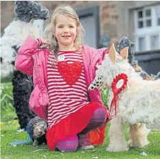  ?? ?? Newburgh girl Juliet Justice enjoys meeting fluffy creations at Elie’s scarecrow festival on Toll Green, May Day 2015.