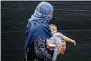  ?? AP PHOTO/ANDREW HARNIK ?? A woman evacuated from Afghanista­n steps off a bus with a baby as they arrive at a processing center in Chantilly, Monday, Aug. 23, 2021, after arriving on a flight at Dulles Internatio­nal Airport.