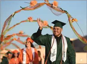  ?? RECORDER PHOTO BY CHIEKO HARA ?? A graduating senior waves to family and friends after passing under flower arches Thursday during Portervill­e High School’s 119th Commenceme­nt Ceremony at Rankin Stadium.