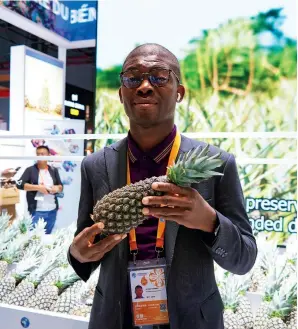  ?? ?? A sta- member shows a pineapple from Benin at the sixth CIIE in Shanghai on 8 November