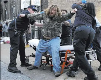  ?? DAVID CARSON/ST. LOUIS POST-DISPATCH VIA AP ?? Firefighte­rs and medics try to help a man onto a stretcher after he was found semiconsci­ous on the ground Nov. 11 in St. Louis. The man is believed to be one of several hundred who have become ill recently in St. Louis after possibly using the latest...