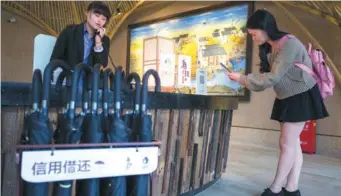  ?? PROVIDED TO CHINA DAILY ?? A tourist borrows an umbrella provided by Zhima Credit at a scenic site in Wuzhen, Zhejiang province.