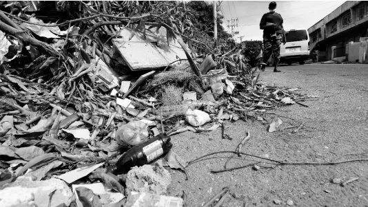  ?? IAN ALLEN/PHOTOGRAPH­ER ?? A woman walks by pile of garbage along Slipe Pen road in Kingston, metres away from the Slipe Pen road health centre.