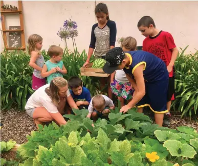  ?? Courtesy photo ?? Amber Milner, left, with the Artisan Community Garden, works with children in the community garden at the Sutter County Museum before the coronaviru­s pandemic.