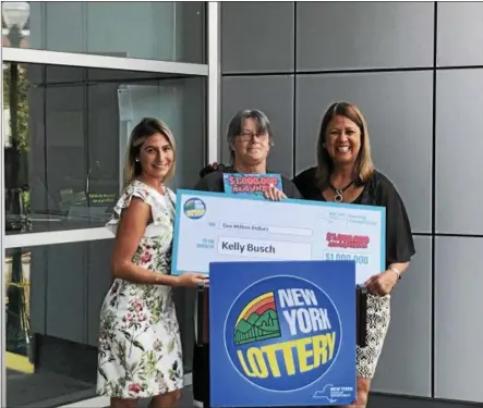  ?? PHOTO PROVIDED ?? Kelly Busch, center, of Ballston Spa picked up her ceremonial $1 million check Wednesday at New York Lottery headquarte­rs in Schenectad­y after winning the top prize in the Mayhem scratch-off ticket game. She’s joined by Lottery’s Anna Lichorat, left, and Yolanda Vega, right.