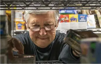  ?? BERNARD WEIL/TORONTO STAR ?? olunteer at the Agincourt Community Services Associatio­n, sorts the can of tuna onto a shelf.