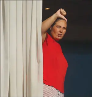  ?? The Associated Press ?? A woman gestures towards the media from her room at the Radisson Blu Edwardian Hotel, near Heathrow Airport, London, Monday. Passengers returning to England from one of 33 “red list” countries must now spend 10 days in a quarantine hotel.