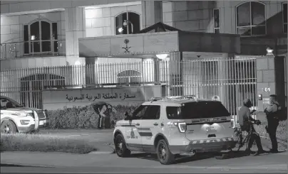  ?? CP PHOTO ?? RCMP question a man on a bike in front of the Embassy of the Kingdom of Saudi Arabia and then searched the area with flashlight­s in Ottawa on Sunday.