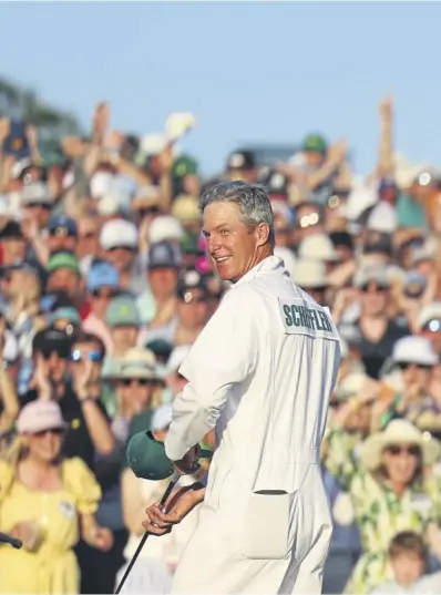  ?? ?? With caddie Teddy Scott by his side, Scottie Scheffler roars with delight on the 18th green. Left, he lifts the trophy after slipping into the Green Jacket