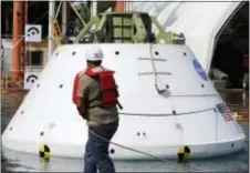  ?? STEVE HELBER — THE ASSOCIATED PRESS ?? A worker corrals a mockup of NASA’s Orion spacecraft, a deeps pace vessel that is slated to eventually travel to Mars, after a simulated ocean splashdown test at NASA Langley Research Center in Hampton, Va., Thursday.