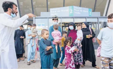  ?? GEMUNU AMARASINGH­E/AP ?? Families evacuated from Kabul, Afghanista­n, walk out of the terminal Friday to board a bus after arriving at Washington Dulles Internatio­nal Airport in Chantilly, Virginia.