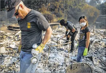  ?? MARCUS YAM / LOS ANGELES TIMES ?? From left: Jeff Lipscomb, Gabriel Lipscomb, 17, and Rachel Lipscomb, 11, look for items to recover in the wreckage of their burned home on Wednesday in Ventura, Calif., where a major blaze started on Dec. 4.