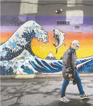  ?? PETER J THOMPSON/NATIONAL POST ?? A pedestrian passes a mural by artist Kinka Izakaya on Loretto Lane at Bloor Street in Toronto Thursday. As restrictio­ns are eased across the country, concerns are emerging about a potential second wave of COVID-19.