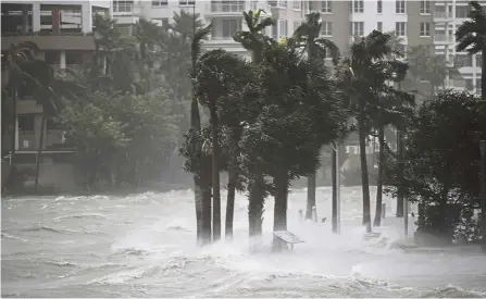  ?? — AFP ?? Storm surge: Water flowing out of the Miami River to flood a walkway as Hurricane Irma passes through in Miami, Florida.