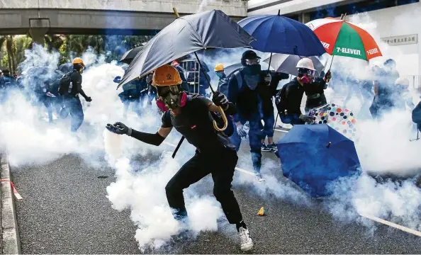  ?? FOTO: JEROME FAVRE/EPA-EFE/SHUTTERSTO­CK ?? Demonstran­ten werfen in Hongkong Tränengasg­ranaten zurück in Richtung Polizei. Erstmals wurde auch scharf geschossen.