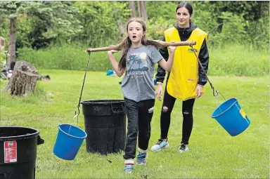  ?? JESSIE MUNRO/SPECIAL TO THE EXAMINER ?? Warsaw Public School’s Makena Cooper, 9, carries buckets of water during the Peterborou­gh Children’s Water Festival at Riverview Park and Zoo in Peterborou­gh on Wednesday. There were 36 learning stations on the importance of water.