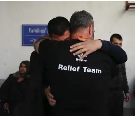  ?? ?? Palestinia­ns carry the body of one of the dead into the Al Aqsa hospital in Deir al Balah, Gaza; the passports of some of the victims; and two of the World Central Kitchen team comfort each other