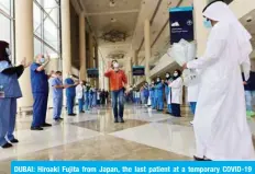  ??  ?? DUBAI: Hiroaki Fujita from Japan, the last patient at a temporary COVID-19 hospital built in downtown Dubai, greets nurses and doctors as he leaves the facility on Tuesday. — AFP