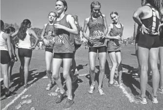  ?? MARK HENLE/THE REPUBLIC ?? The Highland High School cross country runners do the Hokey-Pokey before the start of the Division 1 girls state cross country state championsh­ip,