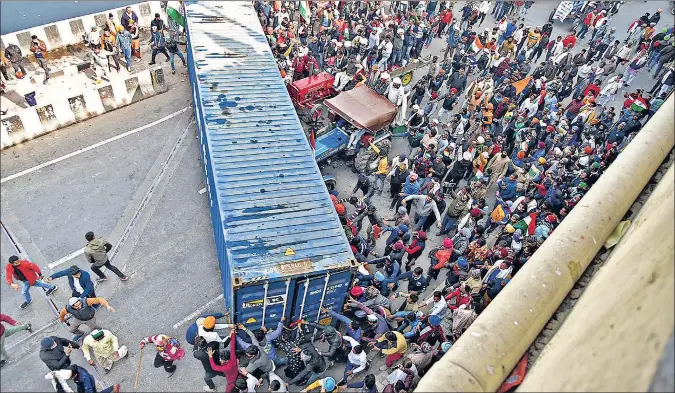  ?? PTI ?? Protesting farmers push aside a cargo container blocking the road near Ghazipur border on Tuesday.