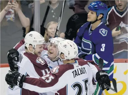  ?? DARRYL DYCK/ THE CANADIAN PRESS ?? Colorado Avalanche’s Jamie McGinn, left, Tyson Barrie and Maxime Talbot celebrate Barrie’s game- winning goal in the third period of Thursday’s game at Rogers Arena. Dejected Vancouver Canucks defenceman Kevin Bieksa skates behind the happy Avs, who...