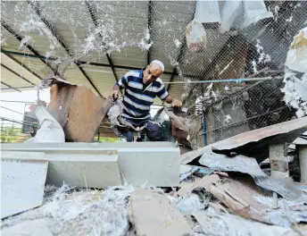  ?? — AFP photo ?? A Palestinia­n man inspects his damaged farm after an Israeli air strike in Gaza City.