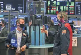  ?? COURTNEY CROW/NEW YORK STOCK EXCHANGE VIA AP ?? Traders Robert Charmak, left, and John Panin work on the floor of the New York Stock Exchange during the DoorDash IPO on Dec. 9. U.S. stocks are wobbling between small gains and losses.