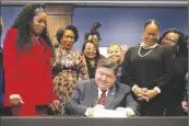  ?? AP PHOTO/CHARLES REX ARBOGAST ?? Illinois Gov. J.B. Pritzker signs into law the Paid Leave For All Workers Act as Illinois House Speaker pro-tem Jehan Gordon Booth (left) Lt. Gov. Juliana Stratton (second from left) and Senate Majority Leader Kimberly Lightford (right) watch on Monday in Chicago.