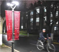  ?? — AFP photo ?? A banner calls for institutio­ns to adhere to the political philosophy of Xi on the campus of Fudan University in Shanghai.