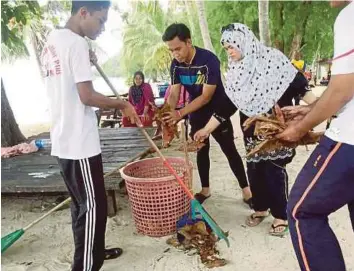  ??  ?? Bergotong-royong membersihk­an pantai Pulau Redang.