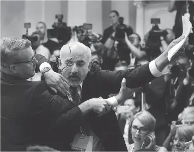  ?? ANTTI AIMO-KOIVISTO / LEHTIKUVA VIA THE ASSOCIATED PRESS ?? Security removes Sam Husseini, a journalist who held up a sign reading “Nuclear Weapon Ban Treaty,” before a press conference with U.S. President Donald Trump and Russian President Vladimir Putin in Helsinki on Monday.