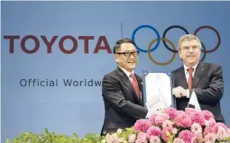  ?? EUGENE HOSHIKO/AP 2015 ?? Toyota CEO Akio Toyoda and IOC President Thomas Bach celebrate a landmark deal in Tokyo after Toyota signed on to be a worldwide Olympic sponsor.