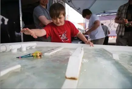  ?? PHOTOS BY VANESSA TIGNANELLI, THE RECORD ?? Arthur Ripley, 8, tests his building skills in Tinker Truck’s boat engineerin­g river challenge, a part of the Open Streets celebratio­n in Waterloo.