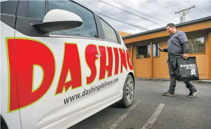  ?? GABRIELA CAMPOS/THE NEW MEXICAN ?? Tyler Huss, lead driver and marketing supervisor for Dashing Delivery, picks up an order for a customer at The Whole Hog Cafe on Monday afternoon. Dashing Deliver will have more competitio­n now that Uber Eats is in Santa Fe.