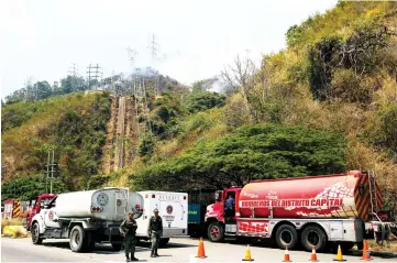  ??  ?? Soldiers block a road during a wildfire near the Boyaca power substation of state-owned electricty company Corpoelec at the Waraira Repano mountain, also know as ‘Avila’, during a power outage in Caracas. — AFP photo