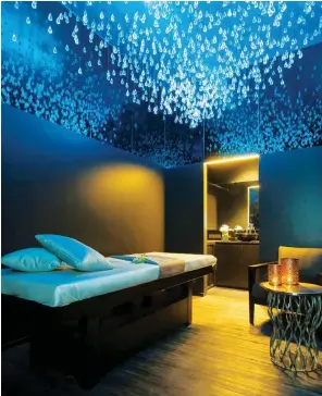  ??  ?? Above, from left: Treatment rooms at Dii Wellness Med Spa feature a lighting installati­on of droplet-shaped crystals; a shoulder massage at the Grand Hyatt Erawan’s I. Sawan spa.