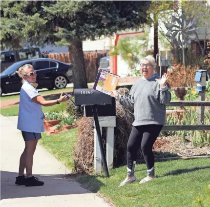  ?? TREVOR HUGHES/USA TODAY ?? Longtime customer Jeanne Simpson mugs for the camera with her mail while USPS carrier Amy Bezerra loads mail into her neighbor’s mailbox in suburban Denver along her route.
