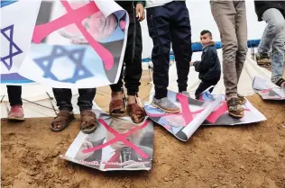  ??  ?? Palestinia­ns step on crossed-out posters depicting Israeli Prime Minister Benjamin Netanyahu and US President Donald Trump during a tent city protest near Khan Yunis in the southern Gaza Strip. (AFP)