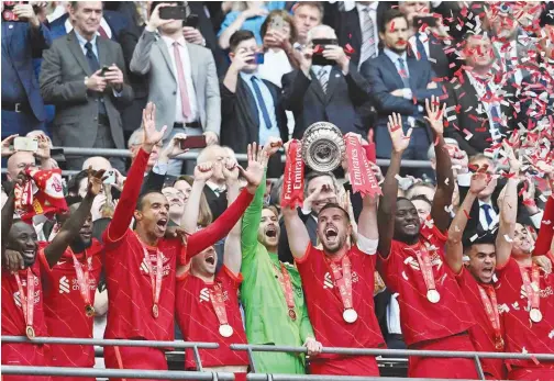  ?? Agence France-presse ?? ↑
Liverpool players celebrate with the trophy after winning the English FA Cup final against Chelsea in London on Saturday.