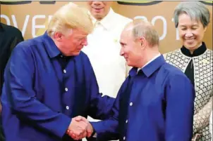  ?? SPUTNIK/AFP ?? US President Donald Trump (left) shakes hands with Russia’s President Vladimir Putin as they pose for a group photo ahead of the Asia-Pacific Economic Cooperatio­n Summit leaders gala dinner in the central Vietnamese city of Danang on November 10.