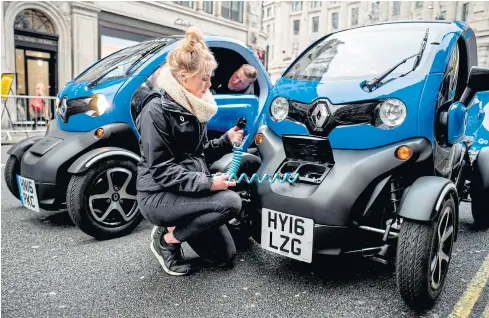  ??  ?? A Renault staff member poses for a photograph with the charging cable of a Renault Twizy during the Regent Street Motor Show in London on November 4, 2017.