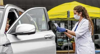  ?? JOHN SPINK/JSPINK@AJC.COM ?? Pat Snellings stays in her car Tuesday after giving a prescripti­on to pharmacist Dawn Sasine at Tuxedo Pharmacy on Wieuca Road in Atlanta. The pharmacy is now providing a drive-thru pickup from their team of masked, gloved employees.