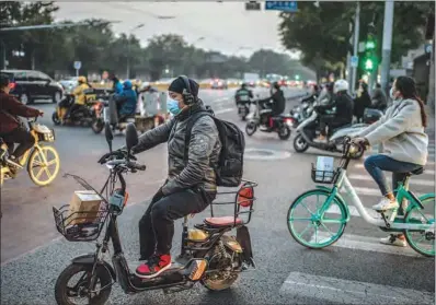  ?? (AFP) ?? People wearing face masks commute during rush hour in Beijing recently.