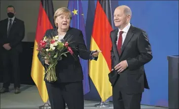  ?? NEW CHANCELLOR Sean Gallup Getty Images ?? Olaf Scholz, right, with Angela Merkel during the official transfer of office in Berlin on Wednesday. The unf lappable Scholz is similar to Merkel in style, even if they are from different parties.