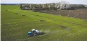  ?? THOMAS PETER / REUTERS ?? A tractor spreads fertilizer on a wheat field near the Ukrainian village of Yakovlivka after it was hit by an aerial bombardmen­t outside Kharkiv on April 5.