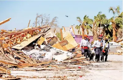  ??  ?? ANGGOTA pencari dan penyelamat melintasi runtuhan puing yang ditinggalk­an oleh Taufan Michael Pantai Mexico, Florida kelmarin. — Gambar Reuters di