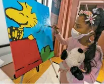  ?? MARY ALTAFFER/ASSOCIATED PRESS ?? Kaley Williams, 8, on Thursday paints a panel of a Peanuts mural to be placed in the outpatient pediatric floor of One Brooklyn Health at Brookdale Hospital. The pandemic won’t stop the Peanuts gang from marking an important birthday, and they’re hoping to raise the spirits of sick kids while they celebrate.